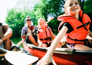 A group of kids sit in a kayak with their parents.