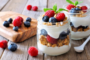 Yogurt parfaits are shown with blueberries, granola and raspberries.