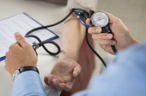 A person gets their blood pressure measured by a medical professional.