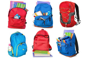 Six backpacks filled with various school supplies are shown.