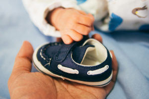 A hand holds a baby's shoe.