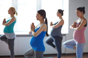 Four pregnant women are doing prenatal yoga together.