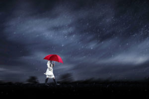 A woman with a red umbrella walks into a hurricane.