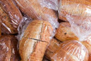 Loaves of bread are shown packaged in a plastic wrap.