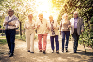 A group of elderly adults walk outside together and smile.