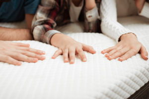 Three people lie on a mattress together.