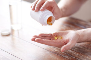 A person pours a fish oil pill into their hand.