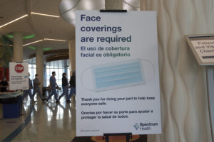 A Spectrum Health sign reads: "Face coverings are required."